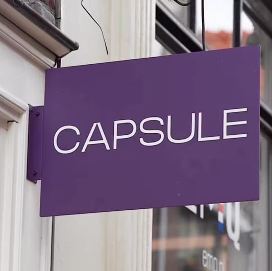 Purple custom rectangular blade sign mounted outside a storefront