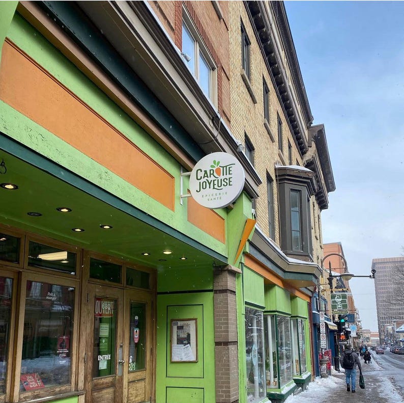 Round blade sign mounted above a green retail storefront