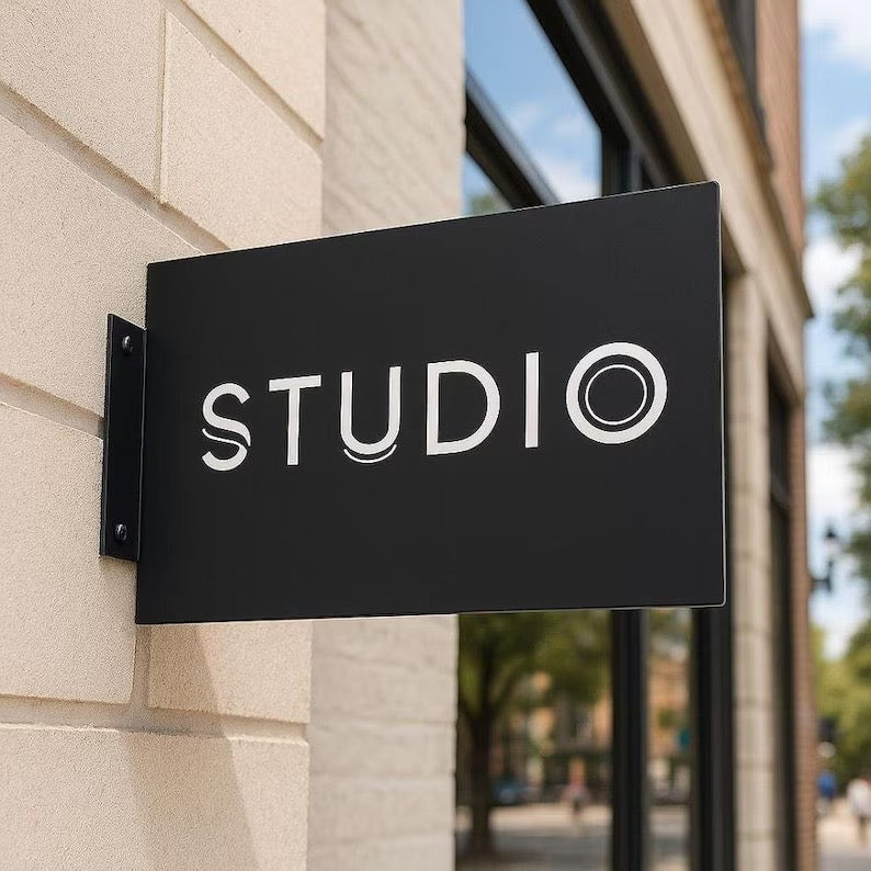 Black custom rectangular blade sign mounted on a stone storefront